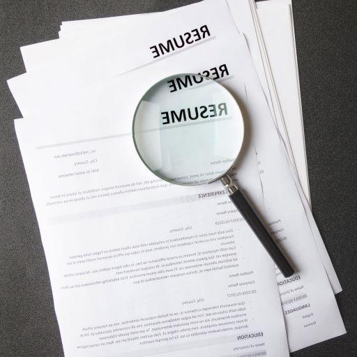 magnifying glass on top of resumes